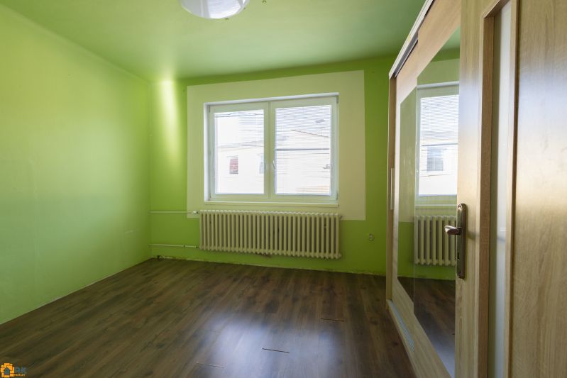 A room in a family house with a wooden decor floor and green walls.