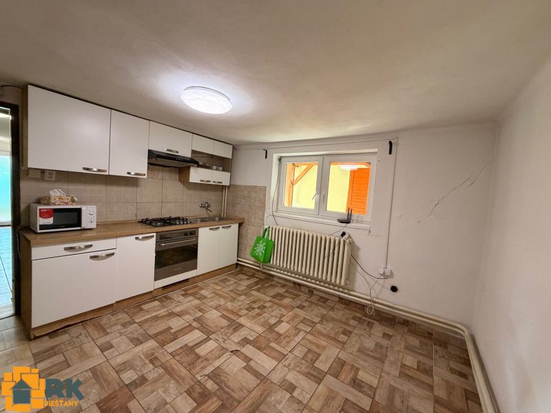 A kitchen in a family house with tiles and white cabinets.