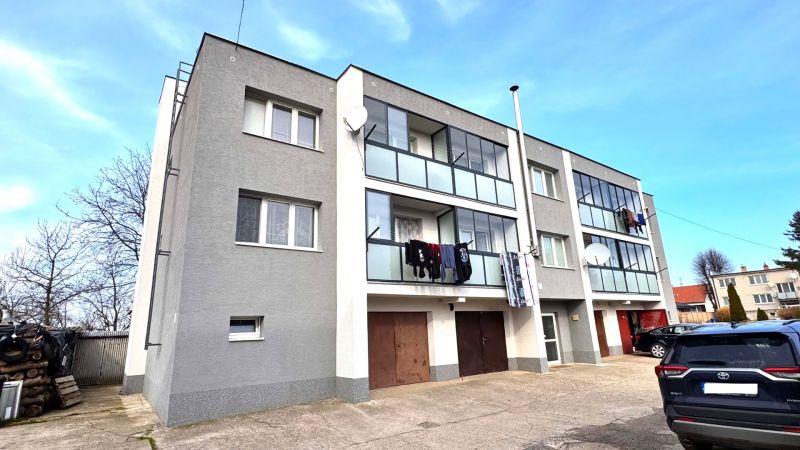 A three-story apartment building with balconies and cars in Hlboké.
