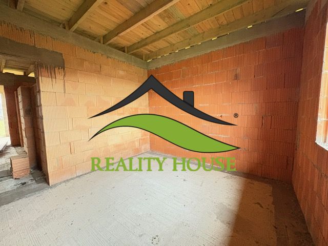 The interior of an unfinished family house with brick walls and a concrete floor.