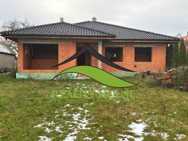 Unfinished family house in Dúbravka, with a black roof and empty windows, in a winter garden.