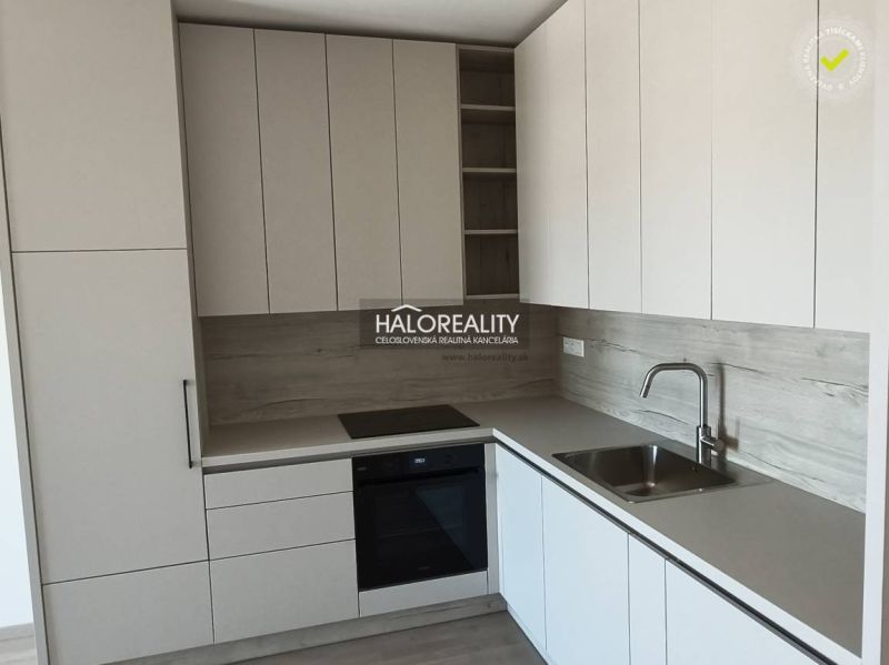 A kitchen in a studio apartment with white cabinets and a wood-patterned floor.