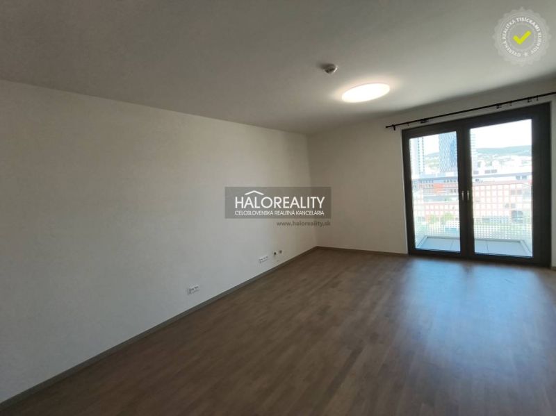 Living room with a kitchen unit and wooden decor flooring in a studio apartment.