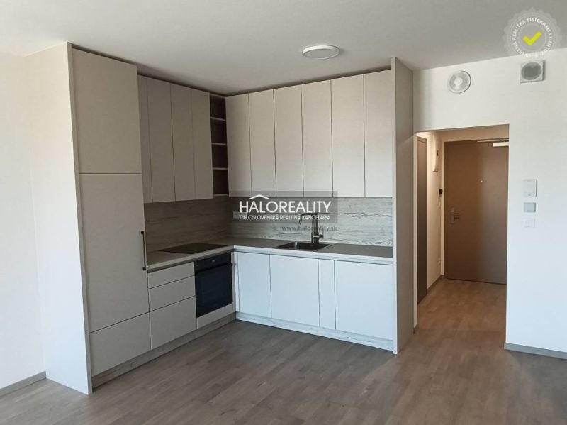 A kitchen in light shades with a wood-patterned floor in a studio apartment.