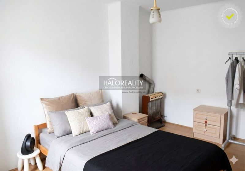 Bedroom in a family house with a comfortable bed, a dresser, and a wardrobe rack.