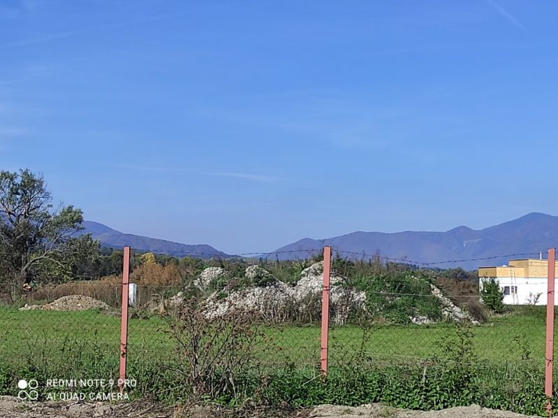 Plots - housing in Príbovce, green meadow with a hill, trees and fencing.