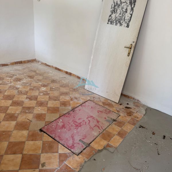 A room in a cottage with a tiled floor and doors without hinges.