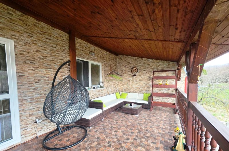 The terrace of a family house in Klokočov with a hanging chair and wicker seating.