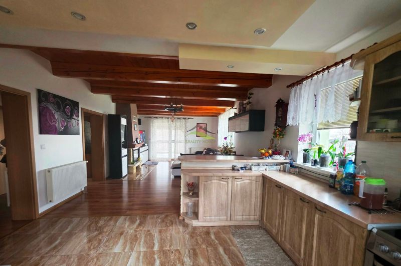 A kitchen with a wood-patterned floor, wooden beams, and decorations in a family house.