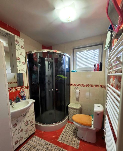 Bathroom with a corner shower, toilet, and floral decor in a family house.