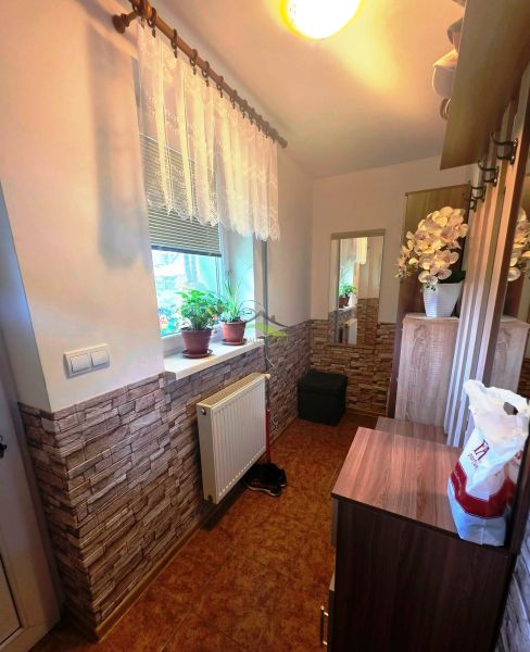 A compact hallway in a family house with brick cladding and flowers on the windowsill.