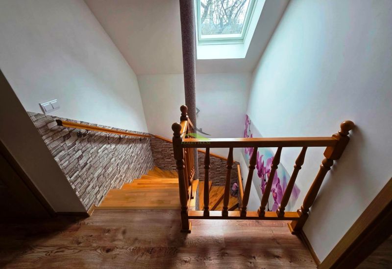 A staircase with a wooden decor, floral wallpaper, and a skylight in a family house.