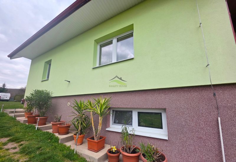 The facade of a family house in Klokočov with flower pots and landscaped greenery in the yard.