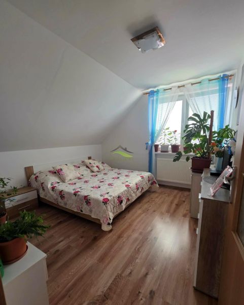 A bedroom in a family house with a wooden decor floor and a bed with a floral bedspread.