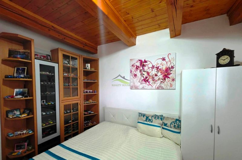 A bedroom in a family house with a showcase for model cars and a wooden ceiling.