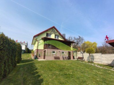 A family house in Klokočov with a grassy garden and a terrace on a sloped plot.