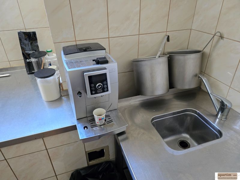 Kitchen corner with a coffee machine, stainless steel sink, and supplies in the catering area.
