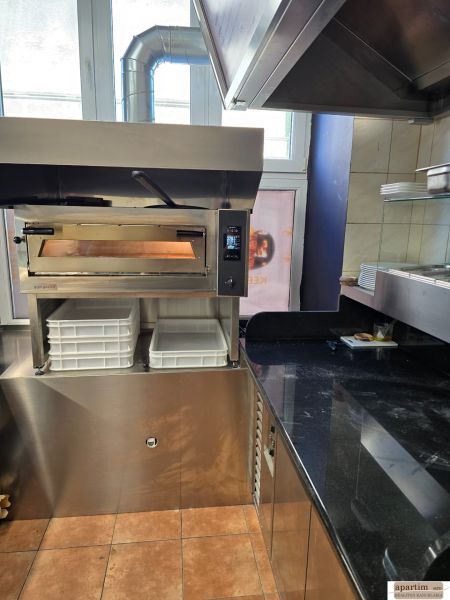 Gastro premises with a pizza oven, stainless steel counter, and ingredient containers.