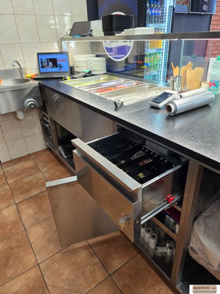 A kitchen unit in a gastro area with stainless steel equipment and a cash register.