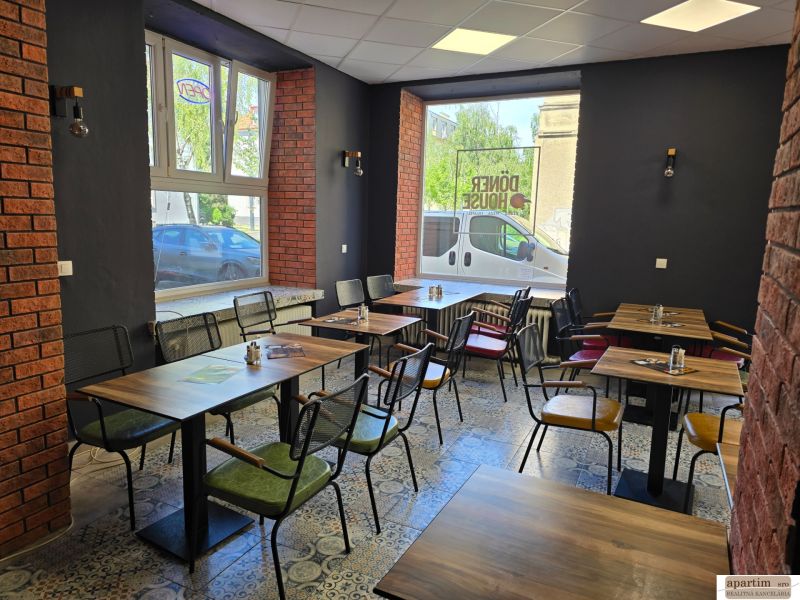 Gastro premises with brick walls, wooden tables, and tiled floors.