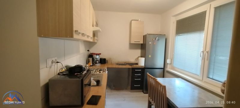 Kitchen in a 2-room apartment with appliances, a dining table, and large windows.
