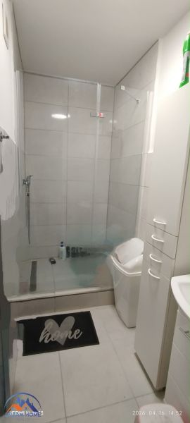 Bathroom in a 2-room apartment with a spacious shower and white furniture.