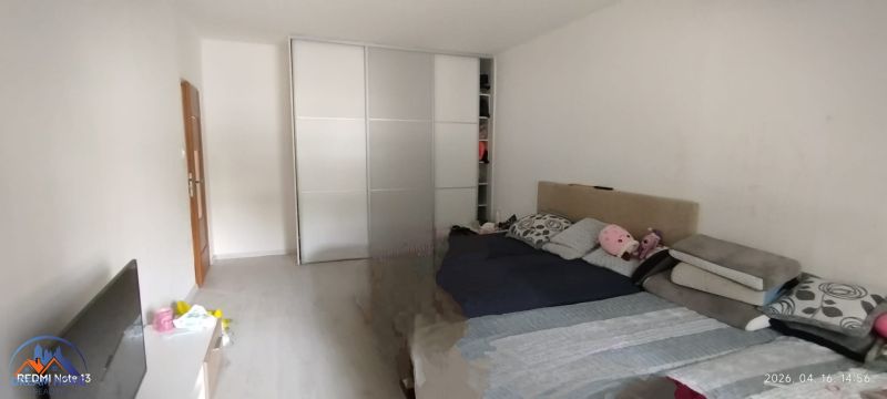 Bedroom in a 2-room apartment with a sliding wardrobe and a bed, floor with wooden decor.