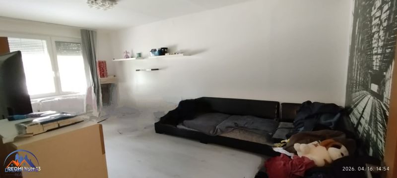 Living room in a 2-room apartment with white walls and a black sofa.