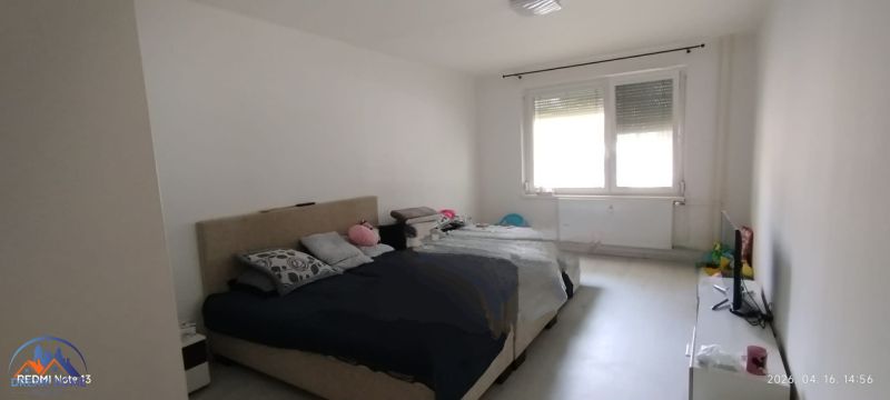 Bedroom in a two-room apartment with a large window and a bed.