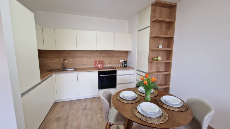 A kitchen in a 2-room apartment with a table and a wooden decor floor.
