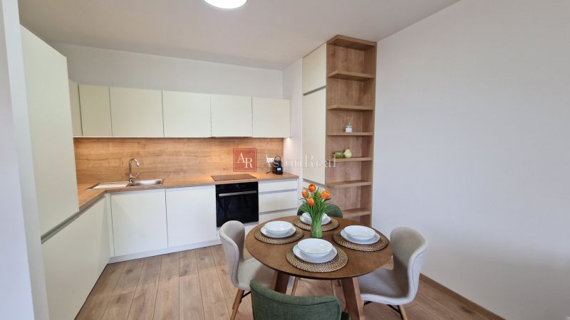 A kitchen in a 2-room apartment with a wooden decor floor and fresh flowers on the table.