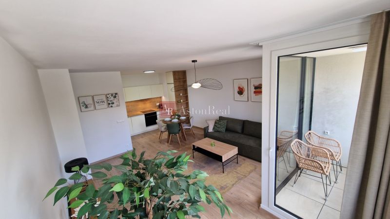 Interior of a 2-room apartment with a wood-decor floor, modern furniture, and a balcony.