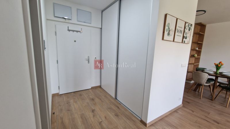 Interior of a 2-room apartment with a wooden decor floor, white doors, and a dining area.