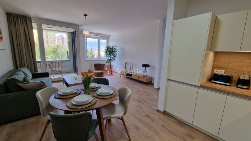 Living room with a kitchenette in a 2-room apartment with a wooden decor floor.
