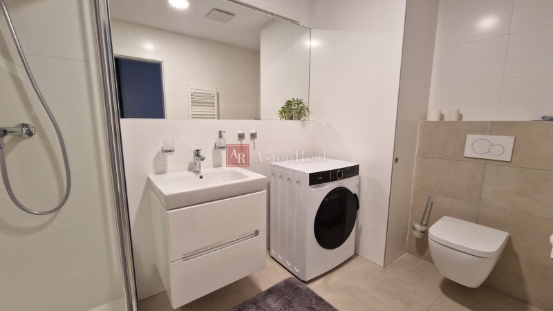 Bathroom in a 2-room apartment with a washing machine, shower, and sink.