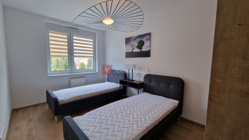 A bedroom in a 2-room apartment with two beds and a floor with a wooden decor.