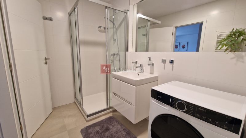 Bathroom in a 2-room apartment with a shower, sink, and washing machine.