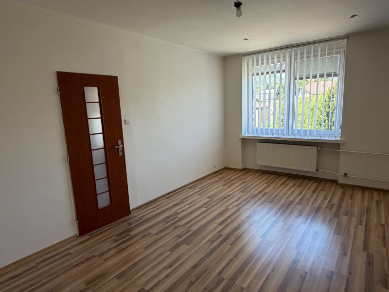 A room in a one-room apartment with a wooden decor floor and a large window.