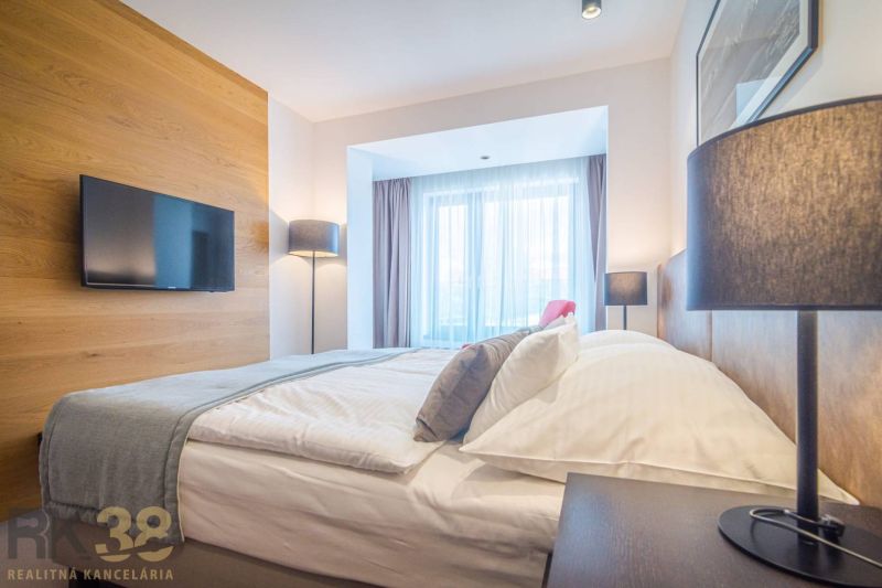 Recreational apartment with a comfortable bed, wooden decor flooring, and large windows.