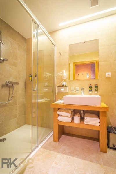 Bathroom in a holiday apartment with a glass shower enclosure and wooden furniture.