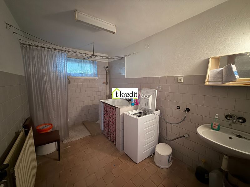 Bathroom with sink, washing machine, and shower in a family house.