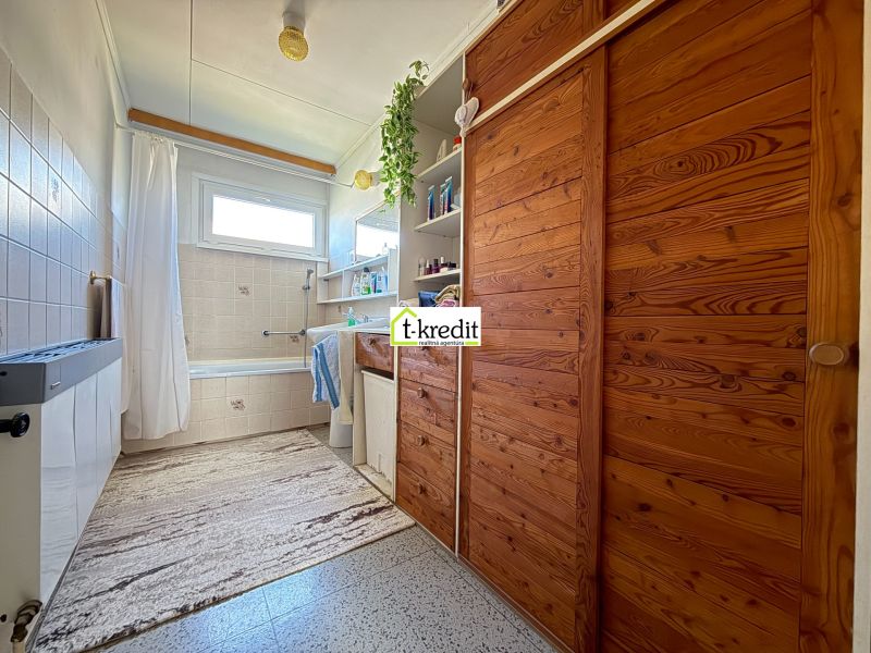 A bathroom with wooden cabinets and a bathtub in a family house.
