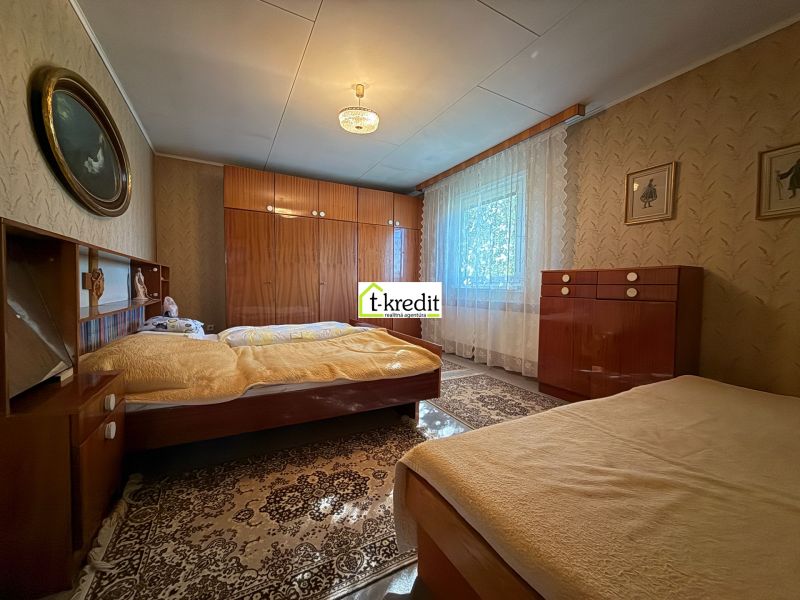 Bedroom in a family house with classic furniture, wooden decor flooring, curtains on the windows.