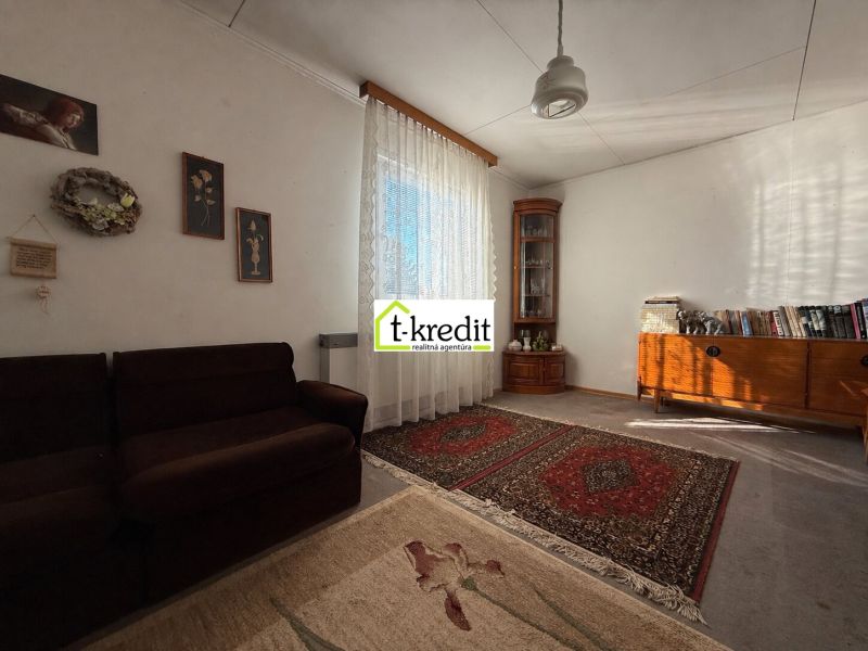 Living room in a family house with carpets, a sofa, and wooden furniture.