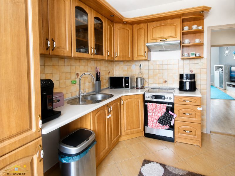 A kitchen in a 3-room apartment with wooden cabinets and a floor with a wooden decor.