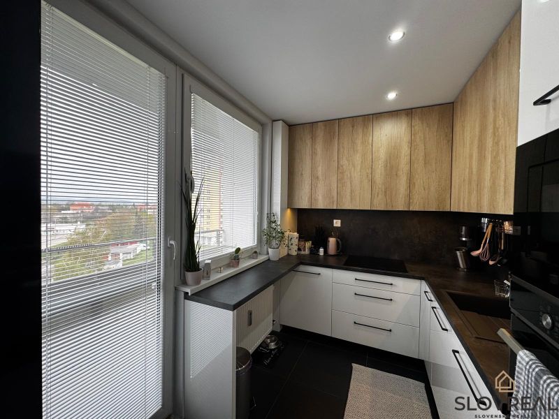A kitchen in a 3-room apartment with a wooden decor floor, white blinds, and a view.