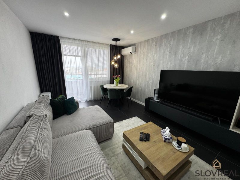Living room of a three-room apartment with a corner sofa and a large television.