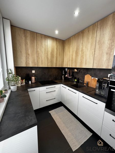 A kitchen with white cabinets and wooden decor in a 3-room apartment.