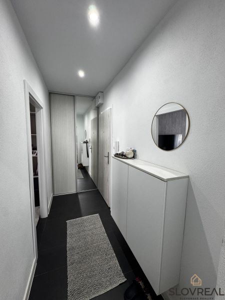 A hallway in a 3-room apartment with a mirrored wardrobe and a decorative carpet.