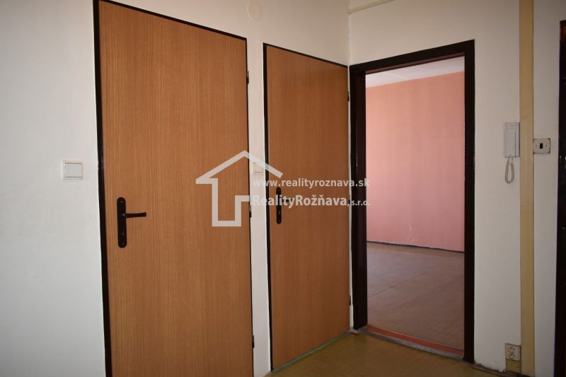 Interior of a 3-room apartment with doors featuring a wooden decor and a telephone on the wall.